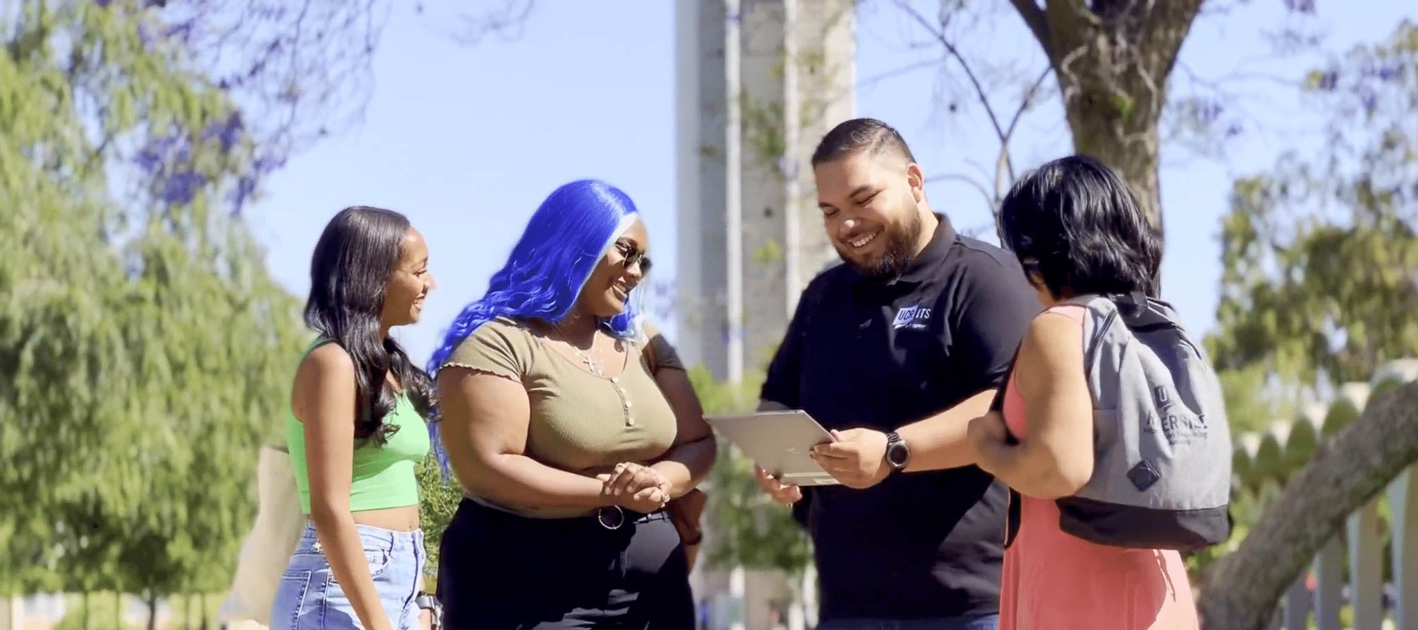 group of students gather around staff member by clock tower
