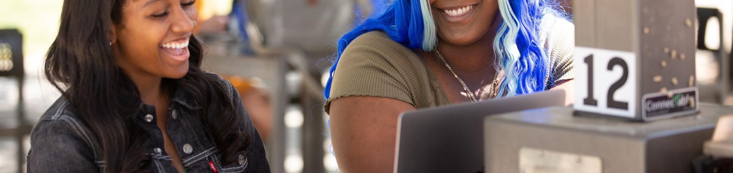two laughing students look at computer