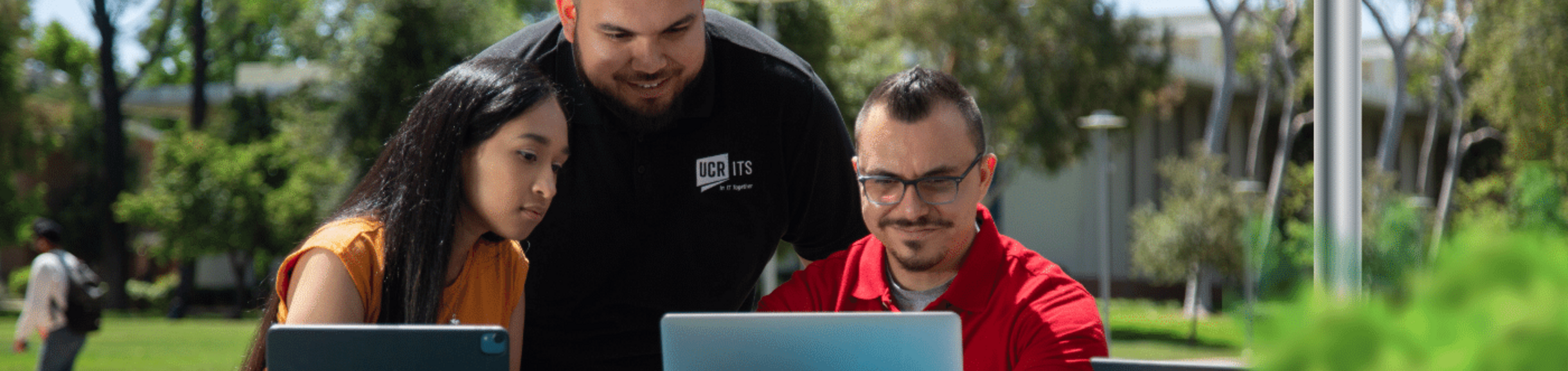 focused staff members overlook two laptops outdoors
