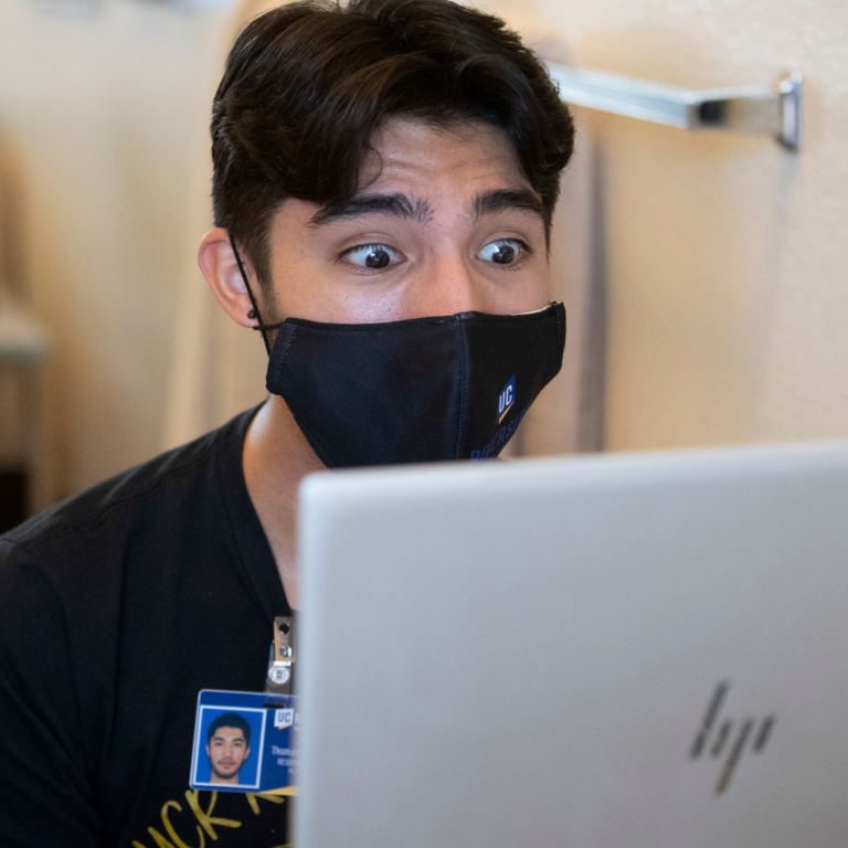 Student in dorms look at laptop in shock