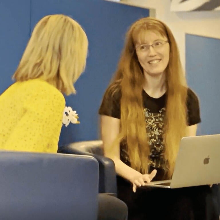 Two ITS employees talk with a laptop