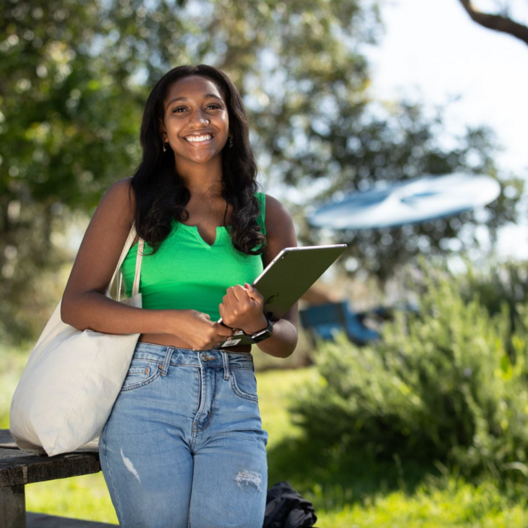 Student in a green shirt holds a tablet