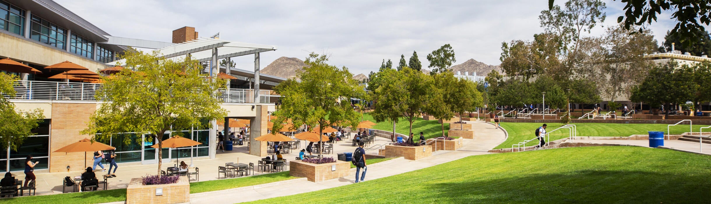 A view of the Highlander Union Building (HUB) Plaza. The HUB building and green grass lawns frame the setting.