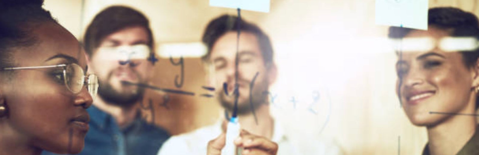 students writing on whiteboard glass
