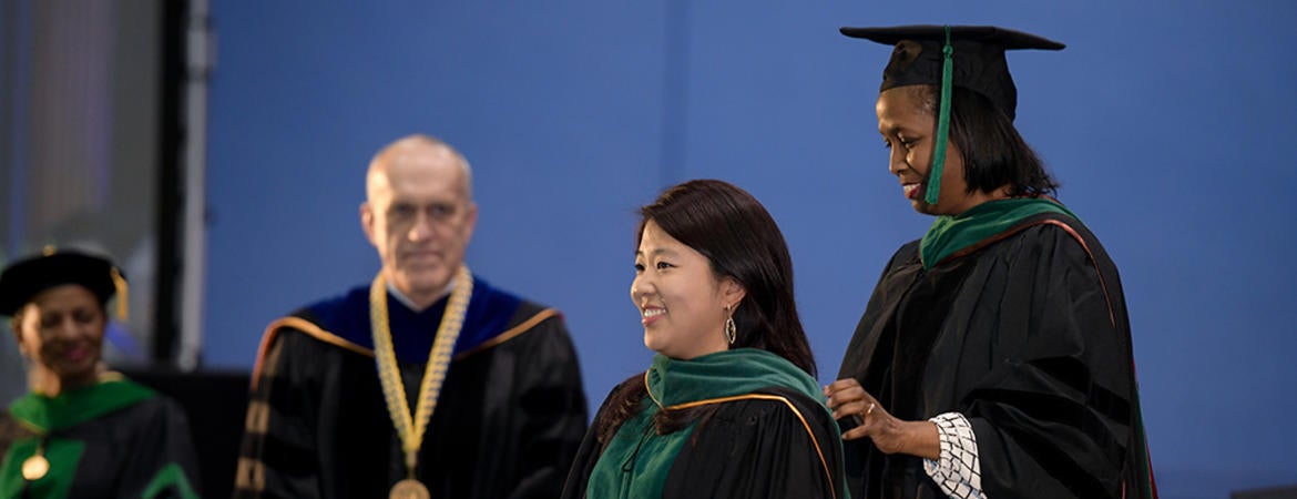 Dr. Emma Simmons hooding a medical student as Chancellor Kim Wilcox looks on.