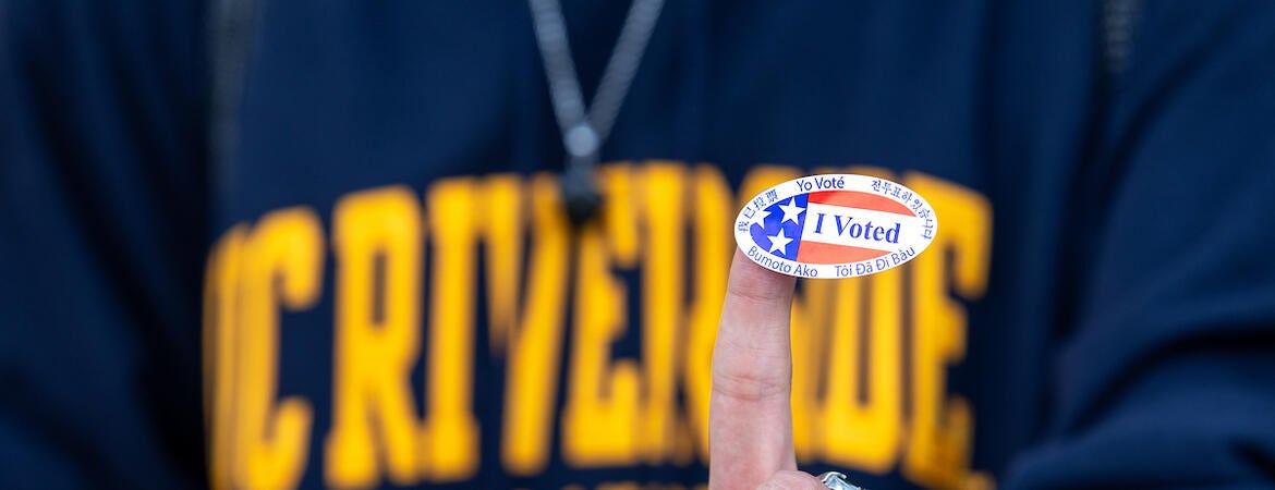 a person wearing a ucr shirt with an I voted sticker on their finger.