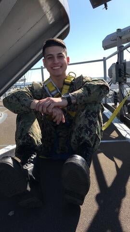 Military officer wearing camo uniform and sitting on ship deck