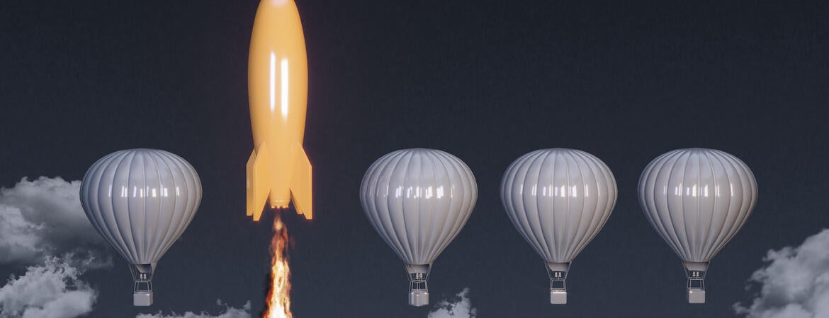 A yellow rocket takes off between gray hot air balloons