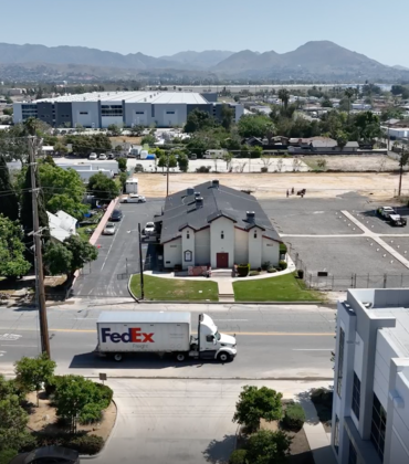Built in 1928, St. Mark’s Missionary Baptist Church is now surrounded by warehouses. (Aerial footage of Valley Truck Farms by Tamara Cedré and Adrian Metoyer III, 2024, courtesy of the artists and A People’s History of the I.E.)