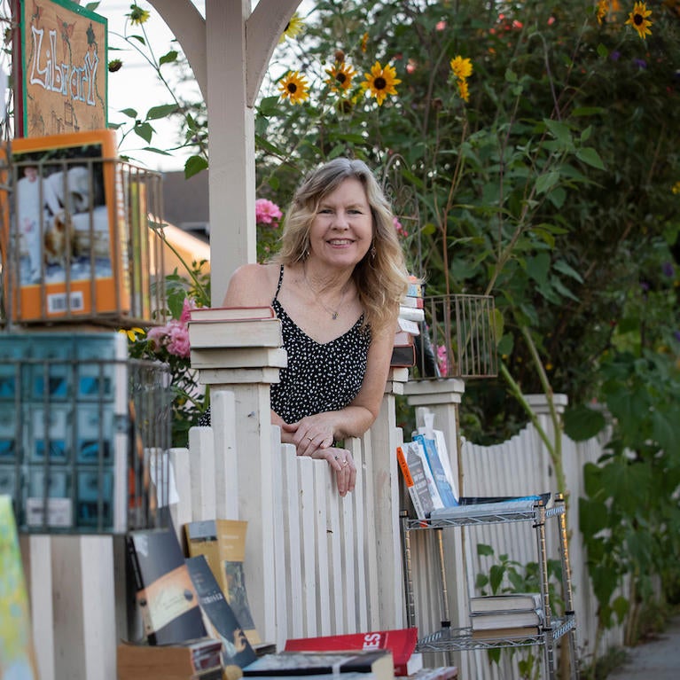 Author Susan Straight leans on her fence next to her fence library.