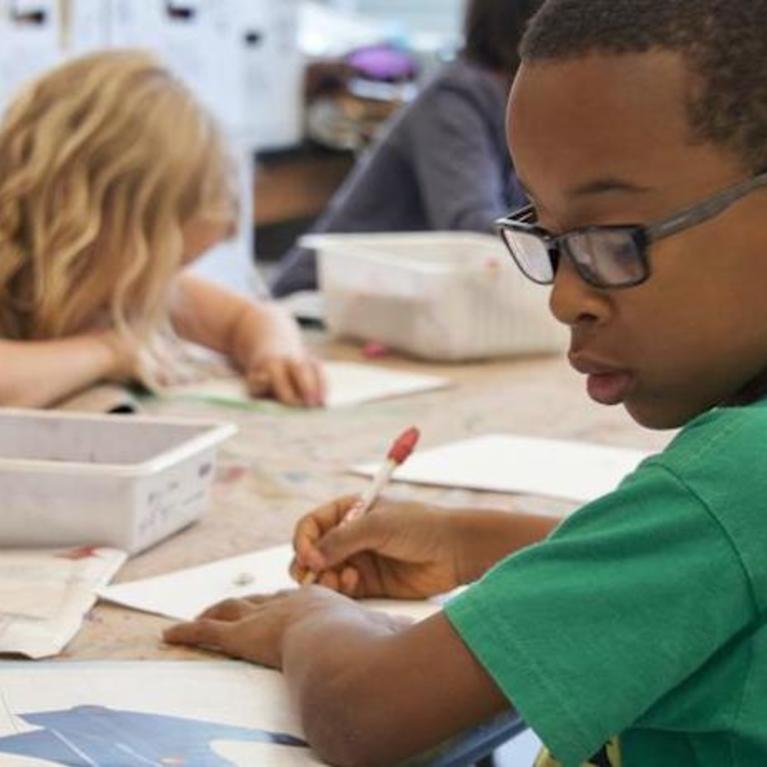A Black student is shown in an elementary school setting amongst white peers