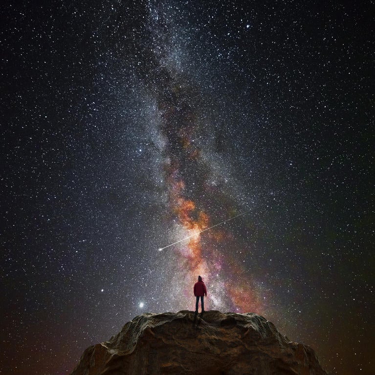 A man on a mountain looks at the stars.