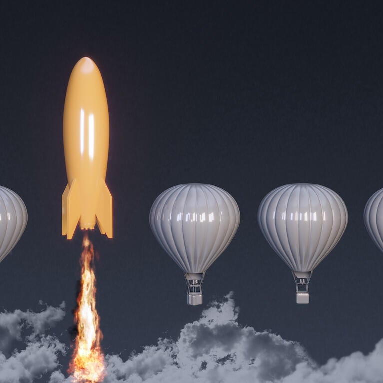 A yellow rocket takes off between gray hot air balloons