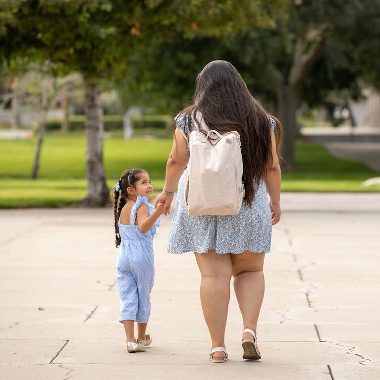 Mother and daughter walking and holding hands.