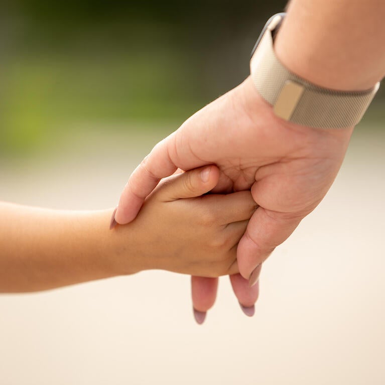 Woman holds hand of child