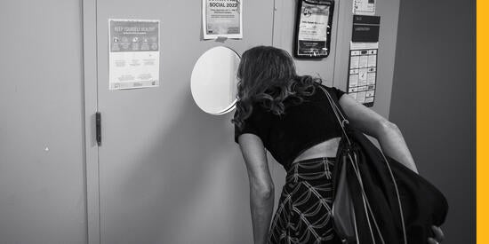 Student looking through a circular window into Tony Norman’s lab