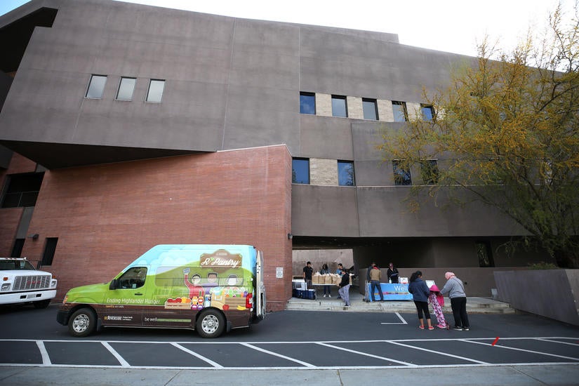 Students line up to receive a bag of groceries from R'Pantry  as they set up in the back of the Arts Building on March 26, 2020 at UC Riverside.  Staff with R'Pantry  handed out bags of groceries to students after the campus was closed to help prevent the spread of the novel coronavirus. (UCR/Stan Lim)