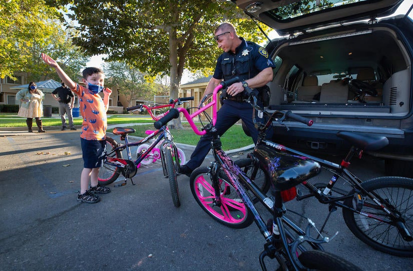 Jet Wilbur, 6, of Riverside, shows his excitement as police officer Paul Dombrowski, with the University of California Riverside Police Department, arrives with bicycles for the children living at UCR’s Oban Family Housing on Friday, September 17, 2021. Officer Dombrowski led the fundraising effort with the financial support of the department’s officers and staff. They raised $500 to purchase bikes for the children. (UCR/Stan Lim)