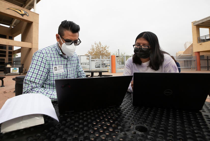 Hector Navarette, assistant director, with UCR’s Educational Talent Search, goes over grades with senior Jenny Pena, 17,  on Thursday, October 7, 2021, at Arroyo Valley High School in San Bernardino. UC Riverside’s Educational Talent Search, San Bernardino grant was recently renewed for five years for $1,642,065.  (UCR/Stan Lim)