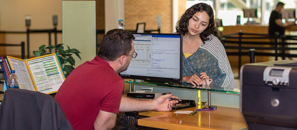 A UCR student gets assistance from a staff member at the Highlander One-Stop Shop (HOSS).