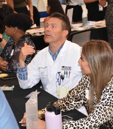 Dr. Aguilera in a white coat sitting at a table at orientation 2024