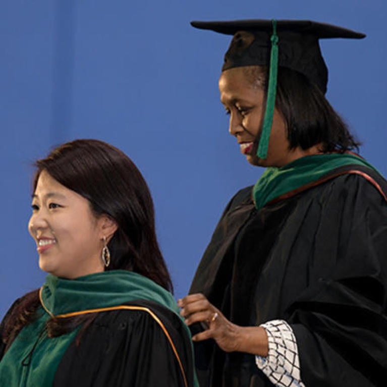 Dr. Emma Simmons hooding a medical student as Chancellor Kim Wilcox looks on.