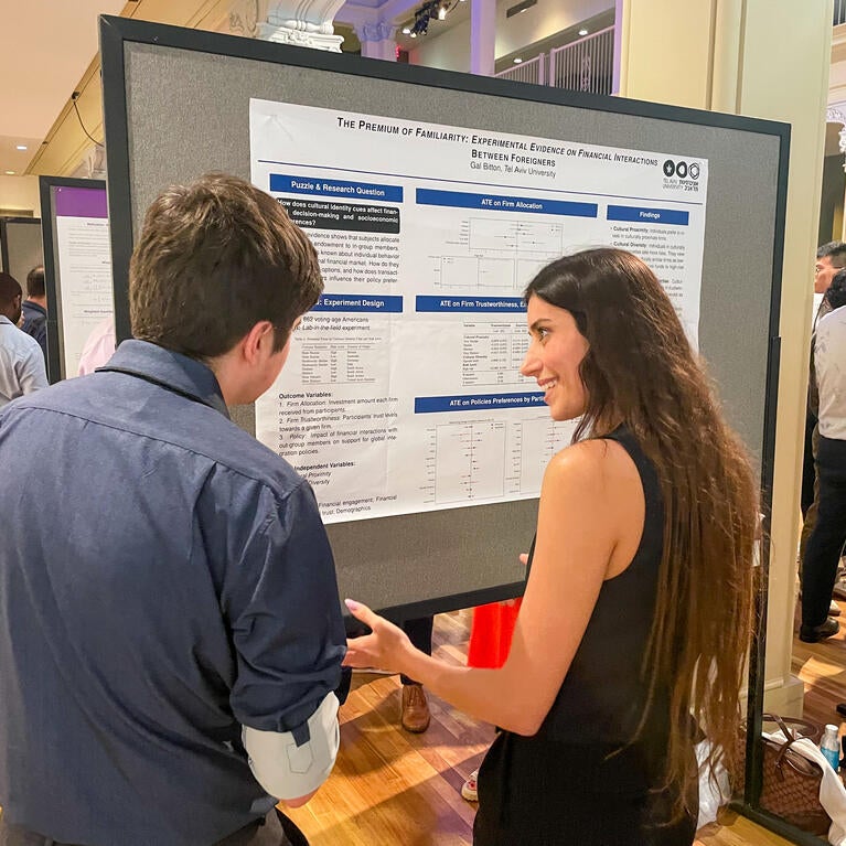 A presenter in front of her presentation board speaking to a guest