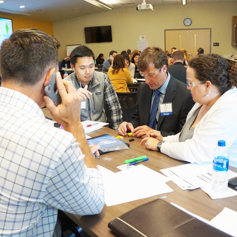 four people at a table working on building blocks