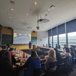 Julianne talking to fellows at symposium