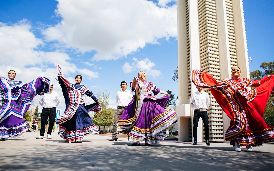 Bailarines chicanos tradicionales actuando frente a la Torre del Campanario en UC Riverside
