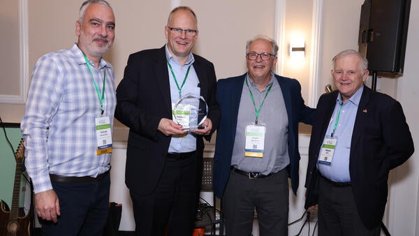 Georgios Karavalakis, Thomas Koch, André Boehman, and Wayne Miller pose together during the Inaugural H2EA-NA Conference banquet as Koch receives a thank-you gift for his keynote address.