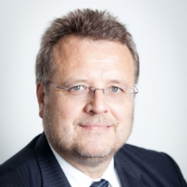 Robert Sykora in a suit and tie wearing glasses in front of white background