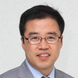 Dr. Young-Jun Moon in suit in front of white background smiling at camera