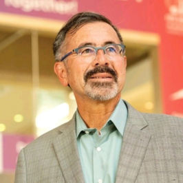 Jim Misener, Senior Director at Qualcomm, wearing a light green shirt and gray jacket.