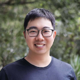 Jiachen Li - man smiling with glasses in front of green background 