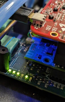 A close-up view of a circuit board with various electronic components illuminated by blue and green lights.