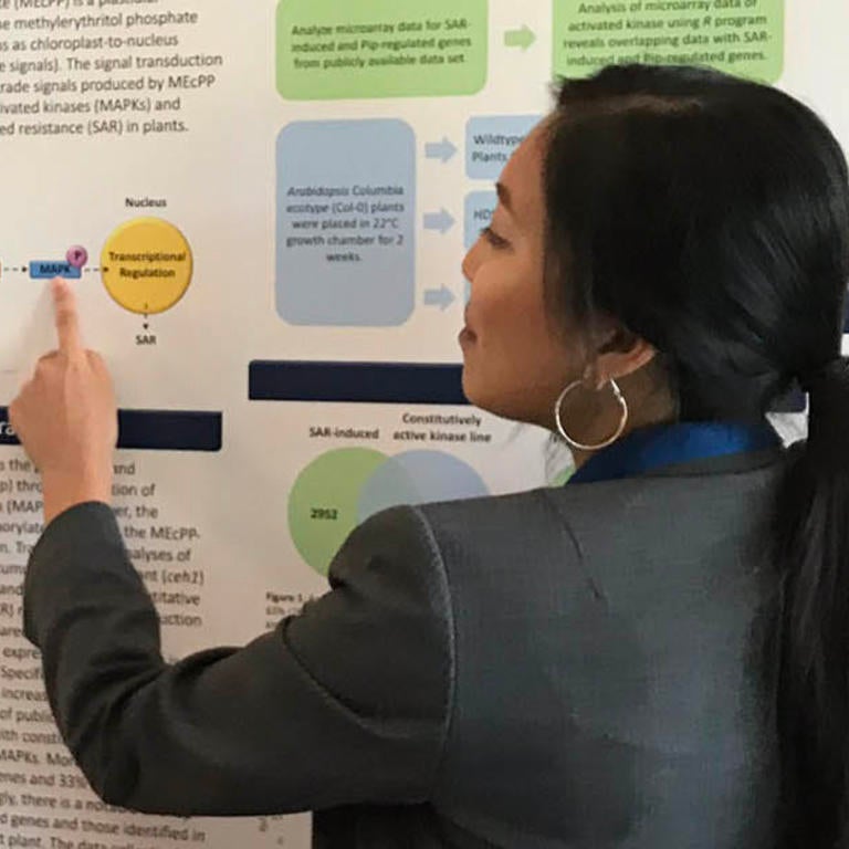 RISE participant in front of research poster