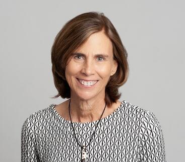 Jennifer Lippincott-Schwartz, a white woman with shoulder length brown hair wearing a black black, white, and red diamond patterned top and a pendant.