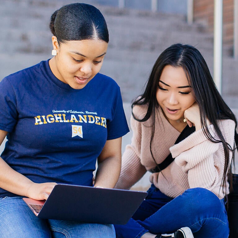 Students On Steps Looking at a Laptop