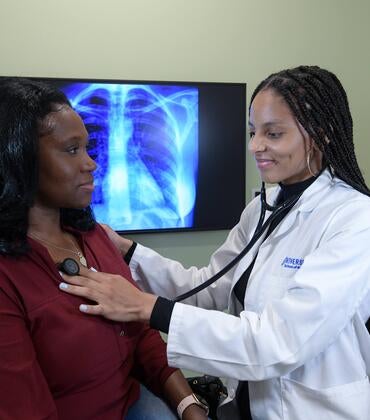 student checking the heart of a patient