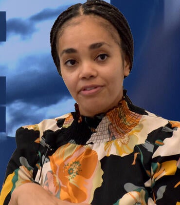 a picture of Dr. Gabrielle Pina in front of a quote from Dr. Martin Luther King, Jr. that reads "The whirlwinds of revolt will continue to shake the foundations of our nation until the bright day of justince emerges.