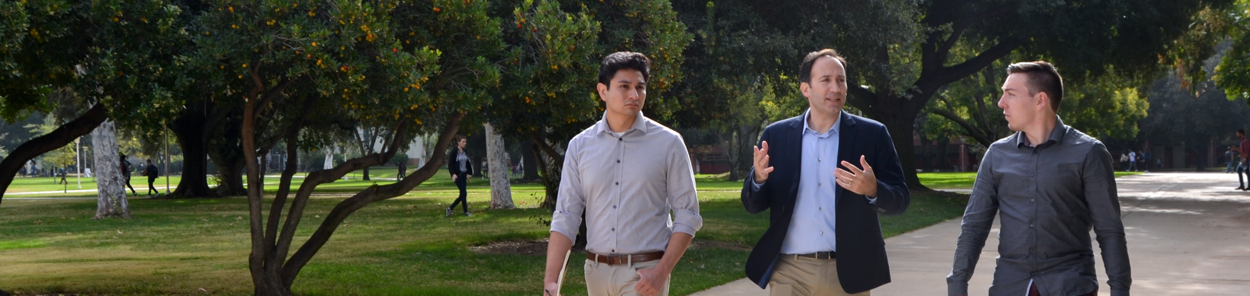 Two male students walking with a male professor