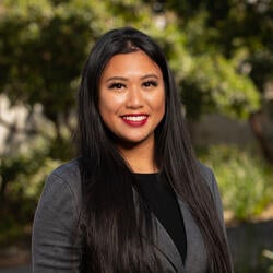 Jessica Saldivar, College Corps Program Manager at UC Irvine, wearing a black shirt with a dary grey blazer smiling for a headshot