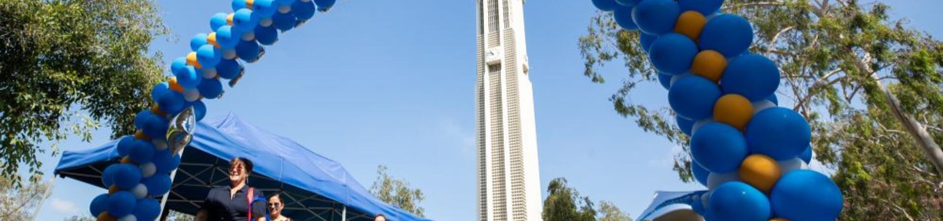 Blue and gold balloon arch in front of the UCR Bell Tower