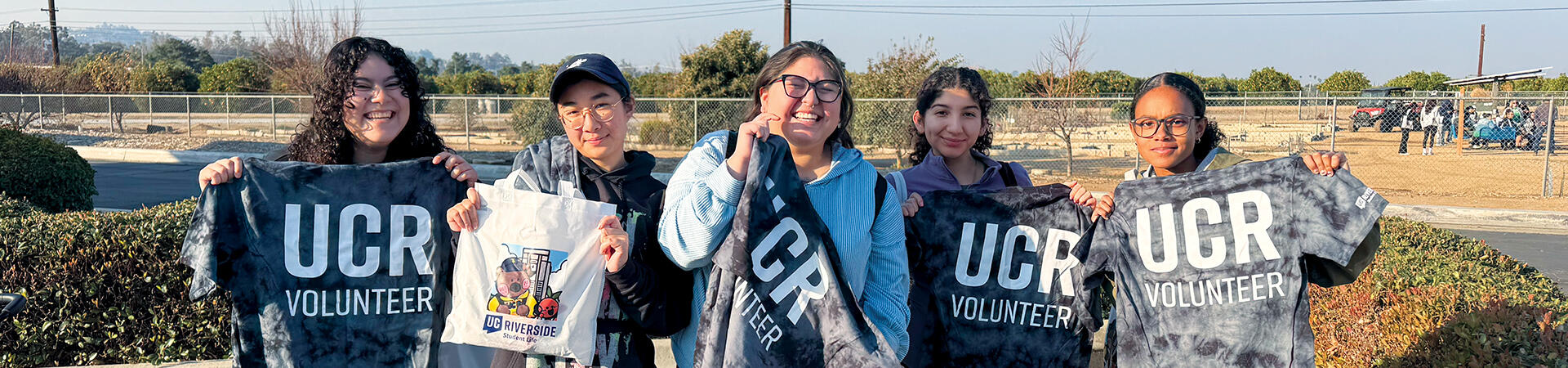 Student holding up UCR Volunteer T-Shirts