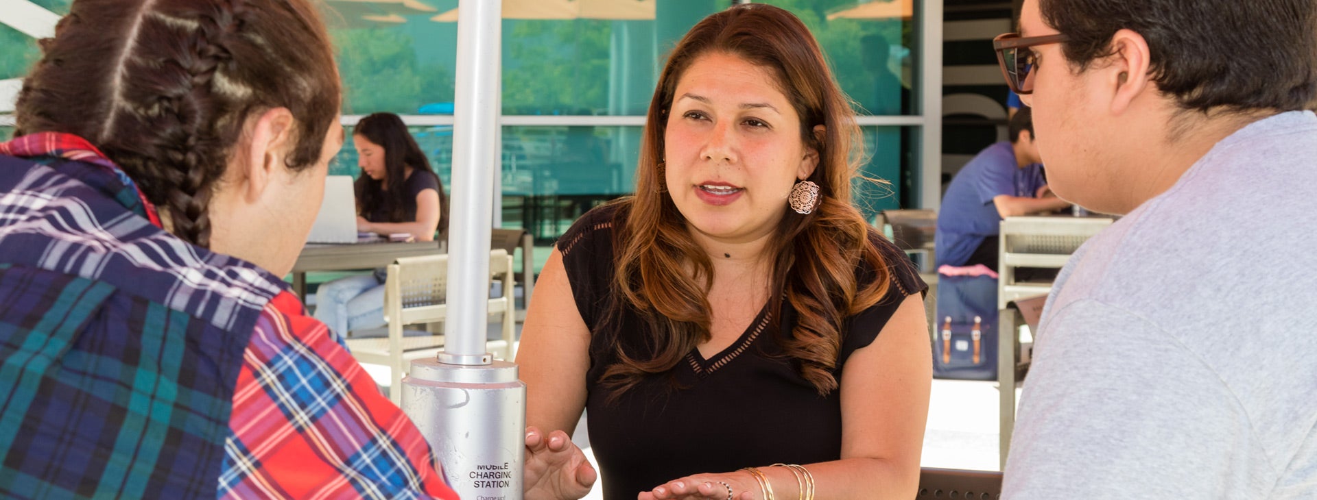 Three TRIO Scholars students have a discussion while sitting at a table near UCR's HUB.