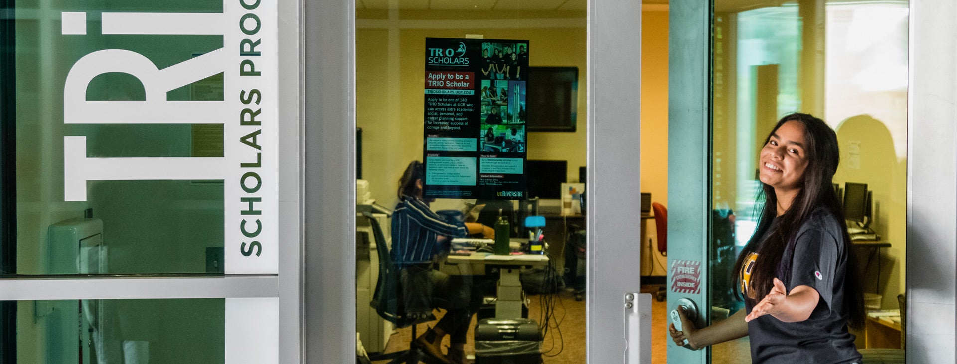 A TRIO Scholars student holds open the door to the TRIO Scholars room at UC Riverside.
