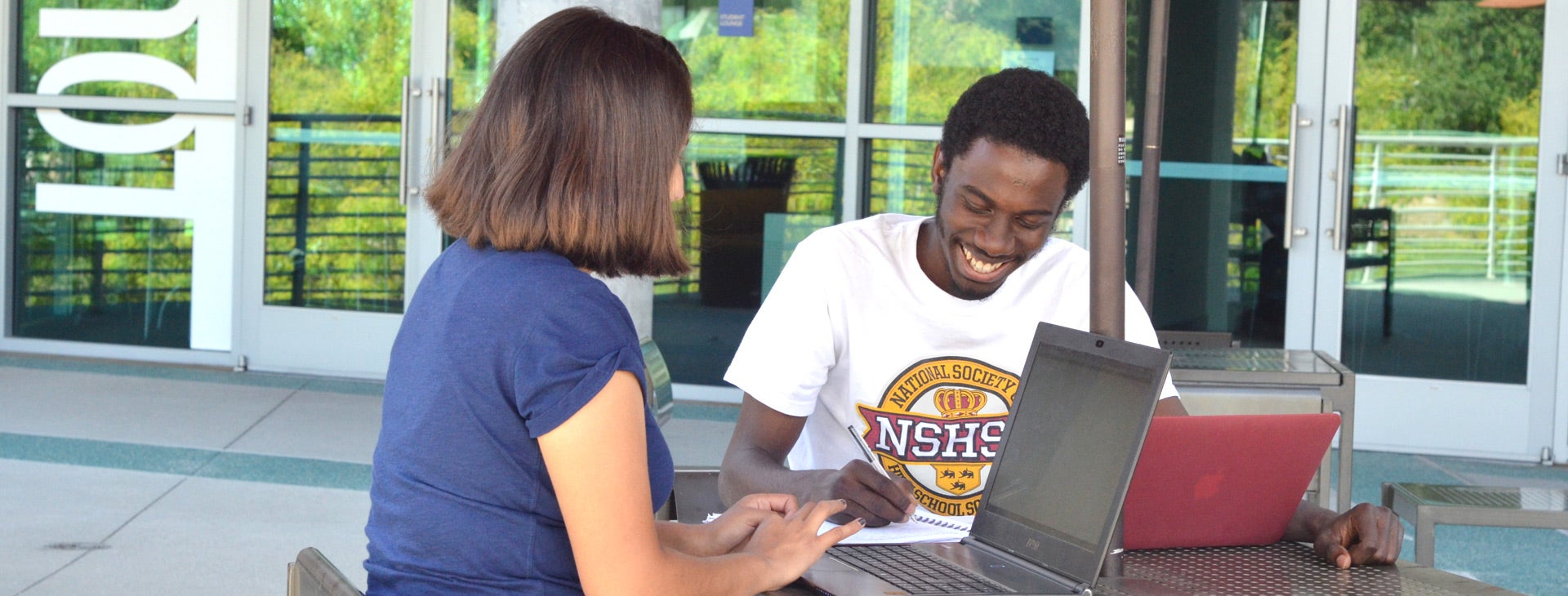 A female and a male TRIO Scholars student study together at a table near the HUB.