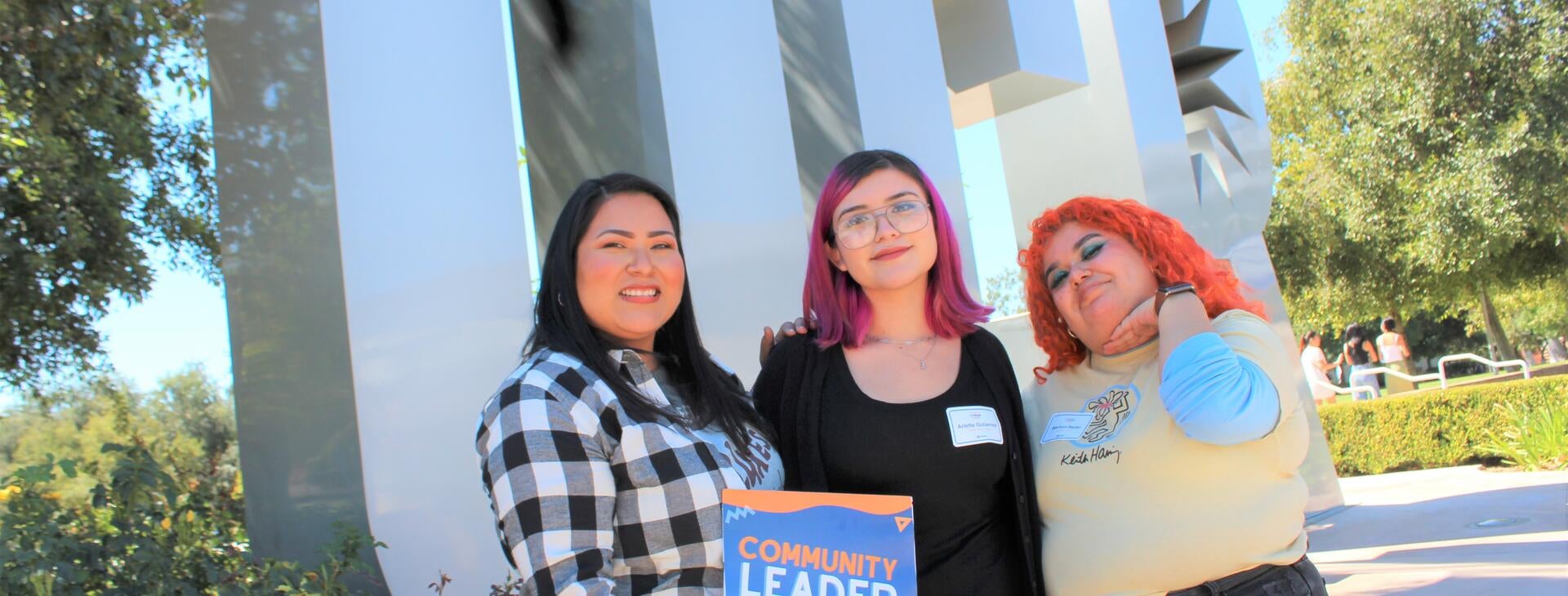 Three students in front of UCR sign