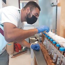 Man in laboratory wearing gloves and mask with tubes